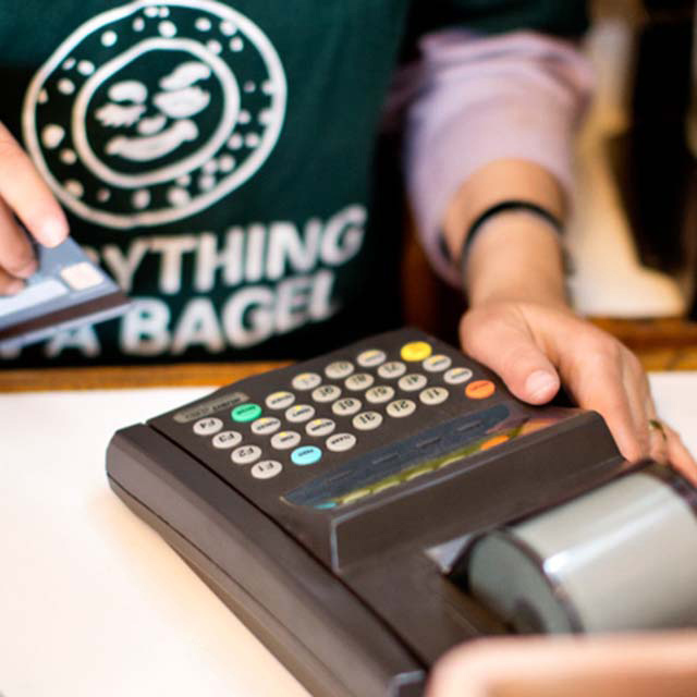 Cashier preparing to slide a customer's credit card at a payment terminal.